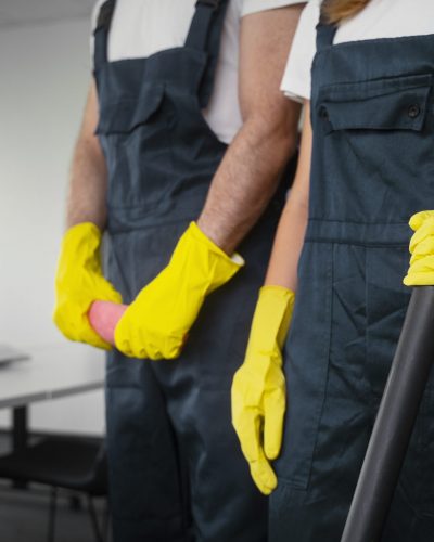 Reinigungsteam mit Besen und Gummihandschuhen bei der Gebäudereinigung